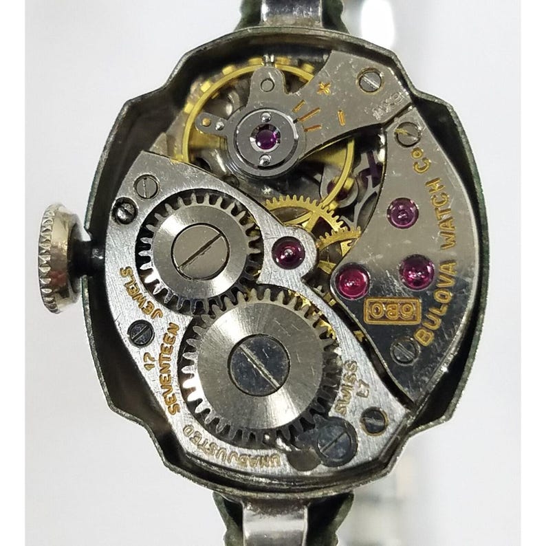 May include: Close-up of the back of a silver Bulova watch with a 17-jewel movement. The watch face is marked "Bulova Watch Co." and "Swiss".