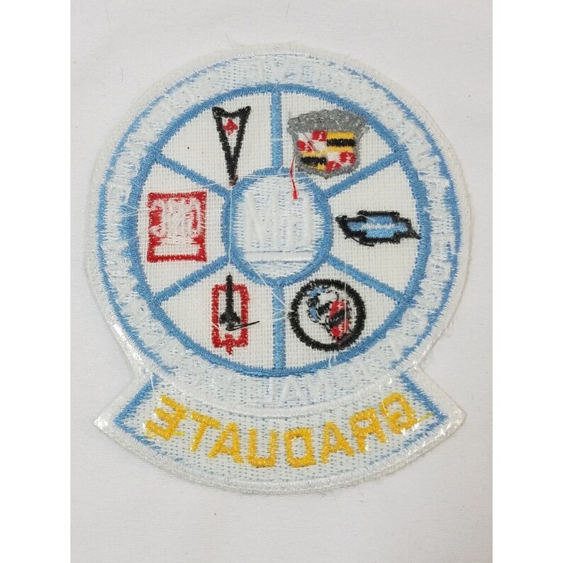 Pode incluir: Um remendo branco bordado com um c&iacute;rculo azul contendo v&aacute;rios logotipos e o texto "TAUQUA" em amarelo. Os logotipos incluem um carro vermelho e branco, um avi&atilde;o vermelho e branco, um carro vermelho e branco, um carro vermelho e branco, um carro vermelho e branco, um carro vermelho e branco e um carro vermelho e branco.