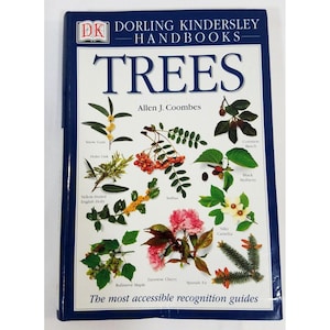 Peut inclure: Un livre à couverture rigide intitulé "TREES" par Allen J. Coombes. La couverture présente une bordure bleue et un fond blanc avec des illustrations de diverses espèces d'arbres, dont Snow Gum, Holm Oak et Japanese Cherry. Le texte "The most accessible recognition guides" est en bas.