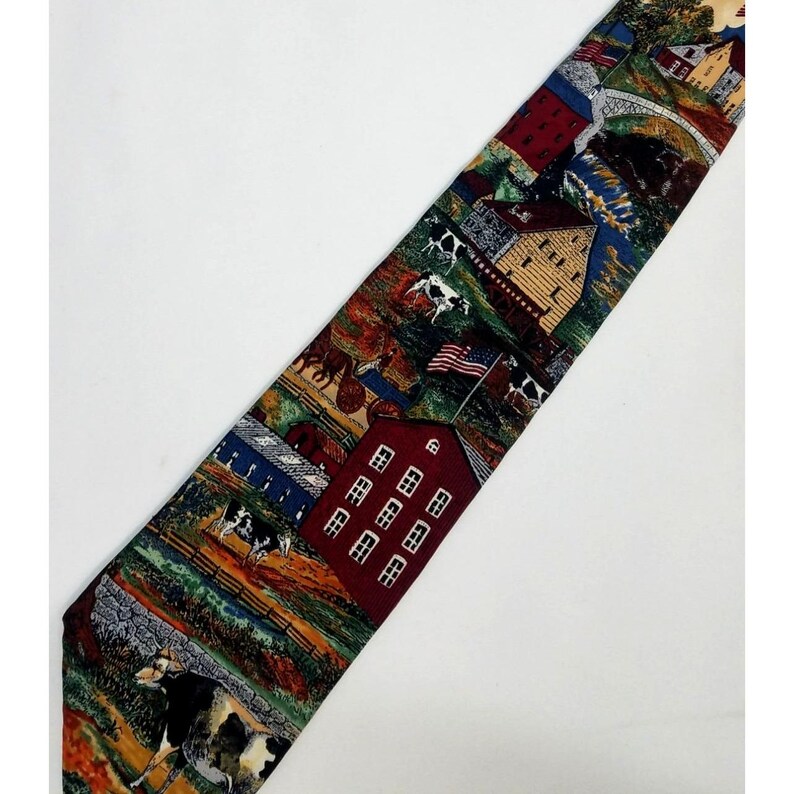 May include: A patterned necktie featuring a rural landscape design. The tie showcases a red barn, cows, an American flag, and other farm elements. The color palette includes shades of red, blue, green, and brown.