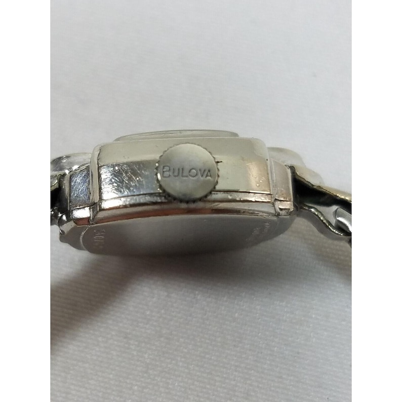 May include: A silver Bulova wristwatch with a square face and a metal band.