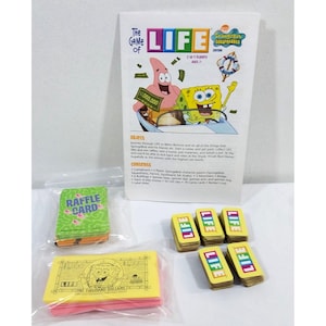 May include: The Game of Life SpongeBob SquarePants edition board game components including a white instruction manual, a stack of green raffle cards, a stack of yellow play money, and several small stacks of yellow cards labeled LIFE.