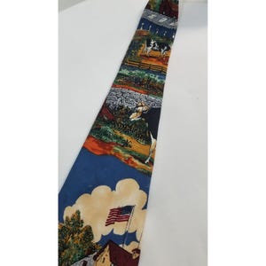 May include: A colorful necktie featuring a rural landscape design. The tie showcases scenes of cows, barns, and an American flag waving in the wind. The tie has a blue background with a variety of colors.