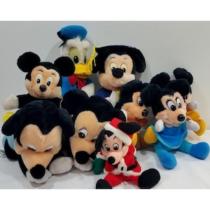 May include: A collection of plush Disney character toys, including Mickey Mouse, Donald Duck, and Mickey dressed as Santa. The toys are in various poses and outfits, with black, red, blue, and yellow colors.