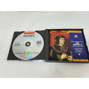 May include: An open CD case with a disc and a booklet. The disc is silver with black text, including "King Richard III" and "Naxos Audiobooks." The booklet features a portrait of a man in historical attire and the title "King Richard III."