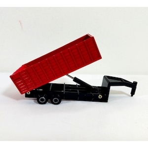 May include: A red toy dump truck with a black chassis and wheels. The truck bed is raised, revealing its interior. The toy is set against a white background.