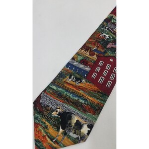 May include: A colorful necktie featuring a rural farm scene. The tie displays cows, barns, fences, and an American flag. The design incorporates shades of red, green, blue, and brown, creating a detailed and vibrant pattern.