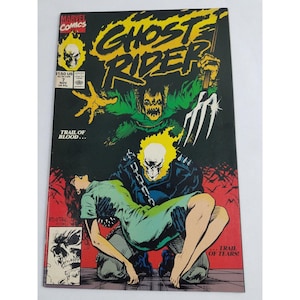 May include: A comic book cover featuring Ghost Rider, a superhero with a flaming skull, holding a woman in his arms. The cover is black and red with the title "Ghost Rider" in large white letters. The text "Trail of Blood..." and "...Trail of Tears!" is also visible on the cover.
