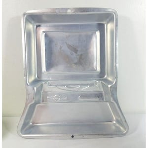 May include: A silver metal cake pan shaped like a vintage computer. The pan has a rectangular screen and a keyboard with a floppy disk drive.