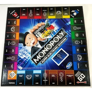 Könnte beinhalten: Ein Monopoly-Brettspiel mit blauem und schwarzem Design. Das Spiel zeigt ein Cartoon-Bild von Mr. Monopoly, der eine Monopoly-Geldkarte und ein rotes Auto hält. Der Text "MONOPOLY SUPER ELECTRONIC BANKING" ist auf dem Brett gedruckt. Das Spiel wird von Hasbro hergestellt.
