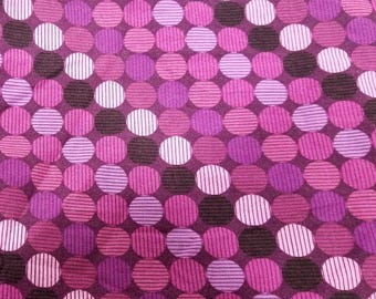 Puede incluir: Primer plano de una tela con un patrón repetitivo de círculos en tonos morados, rosas y blancos. Algunos círculos son sólidos, mientras que otros tienen diseños a rayas. La tela tiene un fondo morado oscuro.