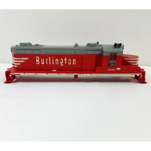 May include: A red and gray model train engine with the words "Burlington" and "5628" printed on the side.