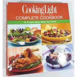 May include: A hardcover cookbook titled "Cooking Light COMPLETE COOKBOOK" with a red and green cover. The cover features images of various dishes, including salads, soup, roasted chicken, and a dessert.