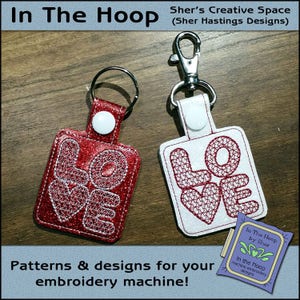 May include: Two keychains with the word "LOVE" embroidered on them. The keychain on the left is red with white stitching. The keychain on the right is white with red stitching. Both keychains have a silver metal ring and a silver metal clasp.