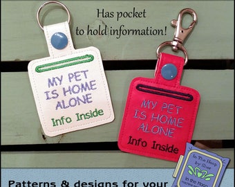 May include: Two white and red keychains with a pocket to hold information. The keychains are embroidered with the text "My Pet Is Home Alone" and "Info Inside".