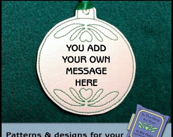 May include: White ornament with green embroidery, featuring the text "You add your own message here".  The ornament is on a green background.  The text "In The Hoop by Sher" is visible in the lower right corner.