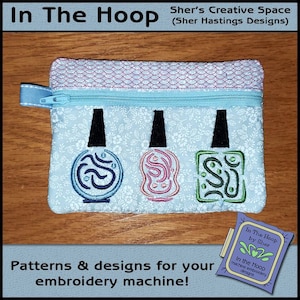 May include: A light blue zippered pouch with a floral pattern. The pouch has three embroidered nail polish bottles with different colored swirls. The text "In The Hoop by Sher" is on a purple label.