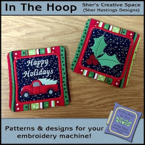 May include: Two embroidered coasters with a red, green, and white striped border. One coaster features a red truck with a Christmas tree in the back, and the text "Happy Holidays". The other coaster features a green holly sprig with red berries. The coasters are on a wooden surface.