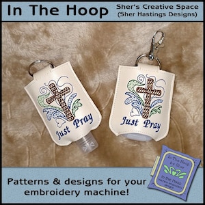 May include: Two off-white hand sanitizer holders with embroidered crosses and the words "Just Pray." One has a bottle inserted. The holders have key rings or a clip. The image also includes text that says "In The Hoop" and "Patterns & designs for your embroidery machine!"
