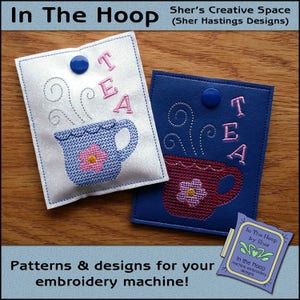 May include: Two embroidered tea-themed pouches. One is white with a blue teacup and pink flower, the other is blue with a red teacup and pink flower. Both have the word "TEA" embroidered in pink.