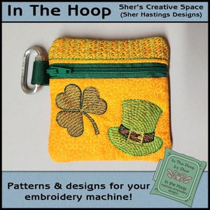 May include: A small orange zippered pouch with a green zipper pull. The pouch has an embroidered shamrock and a green leprechaun hat with a brown belt. The pouch is labeled "In The Hoop by Sher".