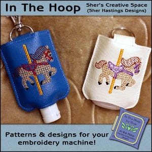 May include: Two embroidered hand sanitiser bottle holders featuring a carousel horse design. The bottle holder on the left is blue and the bottle holder on the right is white. The text "In The Hoop by Sher" is visible in the bottom right corner of the image.