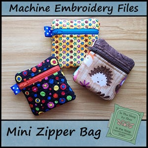 May include: Three mini zipper bags with different fabric designs. The bags are made for machine embroidery and are available in a variety of colours and patterns. The bags are labelled "Mini Zipper Bag" and "In The Hoop by Sher".
