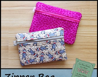 May include: Two zipper bags, one pink with a leopard print and one beige with a monkey print. The bags are machine embroidery files for creating zipper bags. The text "In The Hoop by Sher" and "In the Hoop machine embroidery designs" is on a green label.