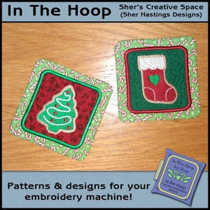 May include: Two embroidered Christmas designs, a green Christmas tree and a red stocking, both with candy cane borders. The designs are on a wooden surface. The text "In The Hoop by Sher" is visible in the lower right corner.