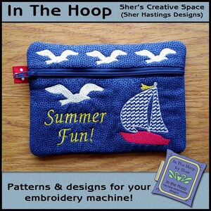 Puede incluir: Una bolsa azul con cremallera con un velero blanco y gaviotas bordadas. La bolsa tiene el texto "Summer Fun!" bordado. La bolsa está sobre una superficie de madera. "In The Hoop by Sher" está escrito en una pequeña etiqueta en la esquina inferior derecha de la imagen.