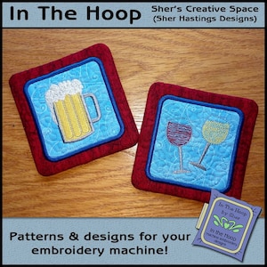 May include: Two embroidered coasters, one with a glass of beer and the other with a glass of wine and a glass of white wine. The coasters are red with a blue center and are on a wooden surface. The text "In The Hoop by Sher" is visible in the lower right corner of the image.