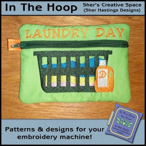 Könnte beinhalten: Eine grüne Reißverschlusstasche mit dem aufgenähten Text "LAUNDRY DAY". Die Tasche zeigt einen grünen Wäschekorb mit bunten Kleidungsstücken darin und eine Flasche Waschmittel. Die Tasche liegt auf einer Holzoberfläche.