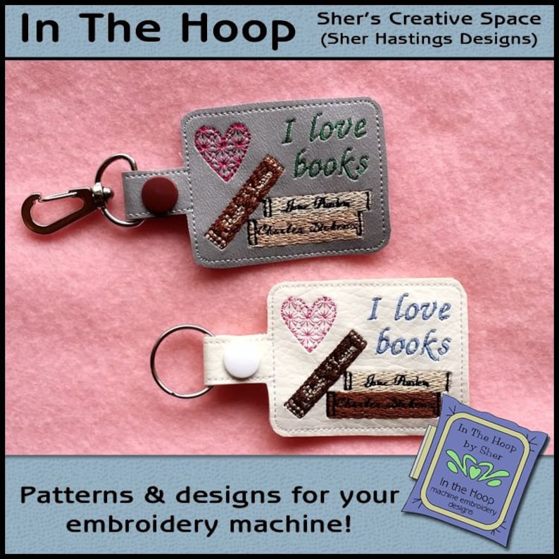 May include: Two keychains with embroidered designs. The keychains are made of gray and white fabric. The designs feature a heart, the words "I love books", and a stack of books. The keychains are perfect for book lovers.
