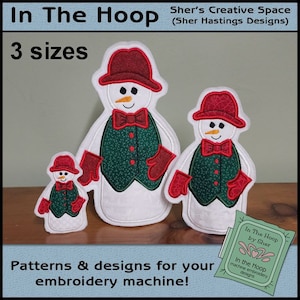 May include: Three embroidered snowman designs in different sizes. The snowmen are wearing red hats, green jackets, and red mittens. The text "In The Hoop by Sher" and "In the Hoop machine embroidery designs" is visible in the image.