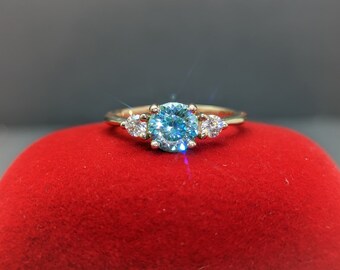 May include: A gold ring with a large blue gemstone surrounded by two smaller white gemstones.