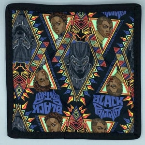 May include: Square, quilted pot holder with a repeating pattern of Black Panther imagery and portraits of women. The design includes geometric shapes in yellow, orange, blue, and green on a black background. The words "Black Panther" are also visible.