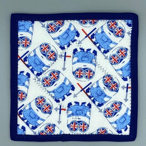 May include: Square fabric coaster featuring a repeating pattern of blue cartoon characters with Union Jack eyes and overalls on a white background. It has a navy blue border.