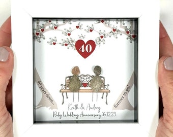 Pode incluir: Uma imagem emoldurada branca com uma cena pintada à mão de um casal sentado em um banco sob uma árvore com corações vermelhos. O texto diz "40 years down... 40 forever to go! Keith & Audrey Ruby Wedding Anniversary 16.12.23"