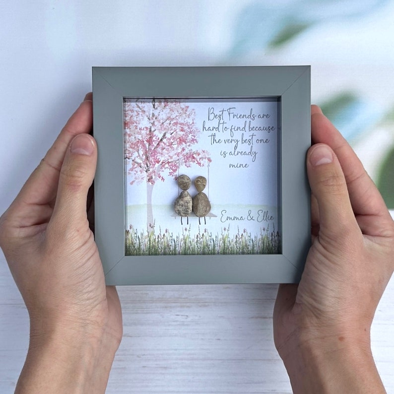 May include: A framed print with a hand-painted illustration of two figures sitting on a swing under a pink-blossomed tree. The text reads "Best Friends are hard to find because the very best one is already mine." The names "Emma & Ellie" are written below the text.