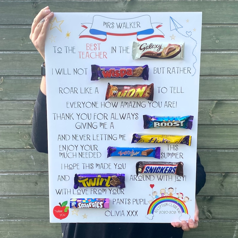 K&ouml;nnte beinhalten: Ein wei&szlig;es Poster mit Text und Schokoriegeln, ein Geschenk f&uuml;r eine Lehrerin. Der Text enth&auml;lt "Mrs. Walker", "Beste Lehrerin" und verschiedene Schokoriegel wie Galaxy, Wispa, Lion, Boost, Flake, Twirl und Snickers. Verziert mit Sternen, einem Regenbogen und einem roten Apfel.