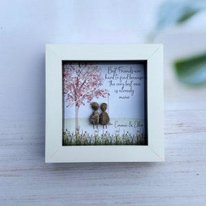 May include: White framed artwork with a pink tree and two pebble people sitting on a swing. The text reads "Best Friends are hard to find because The very best one is already mine" and is signed "Emma & Ellie".