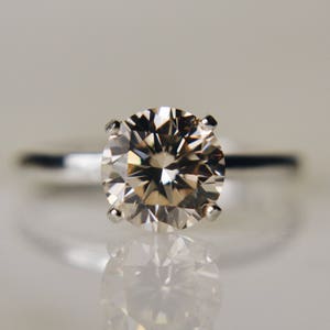 May include: A silver ring with a large, round, clear diamond.