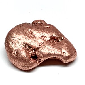 May include: A single, irregular copper nugget with a metallic, reddish-brown luster. The surface features a textured, pitted appearance with small crevices and rounded edges, showcasing the natural, raw form of the solid metal piece.