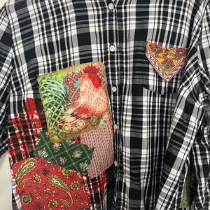 Pode incluir: Uma camisa de flanela xadrez preta e branca com uma variedade de patches de tecido coloridos costurados. Os patches incluem um galo, padrões paisley e desenhos florais.