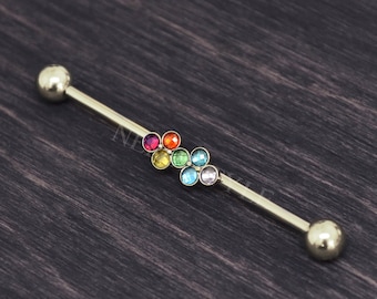May include: A gold barbell with a rainbow of colored gems set in a flower shape.