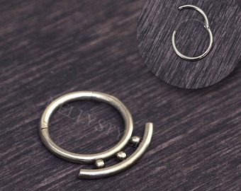 May include: A silver-toned hinged segment ring featuring a curved bar attachment adorned with three small spheres. The jewellery piece includes a circular hoop design with a seamless closure mechanism, presented with a circular inset view.