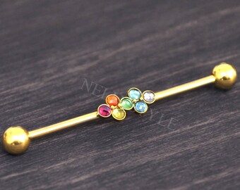 May include: Gold barbell with a cluster of rainbow colored gems. The barbell is a body piercing jewelry item.