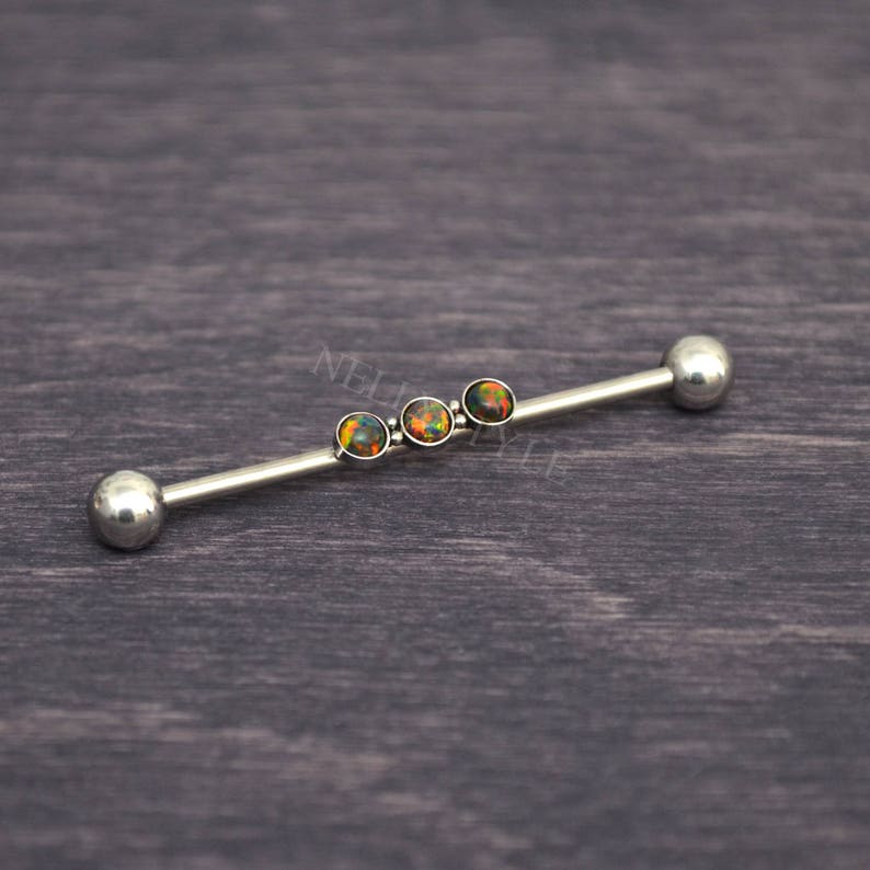Puede incluir: Una barra de plata con cuatro piedras de &oacute;palo iridiscentes. La barra es una joya de piercing corporal.