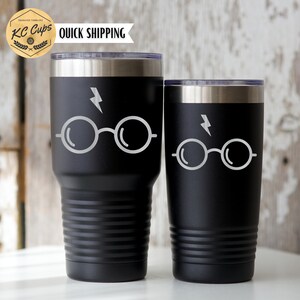 May include: Two black stainless steel tumblers with a white lightning bolt and glasses design. The tumblers are insulated and have a double wall.