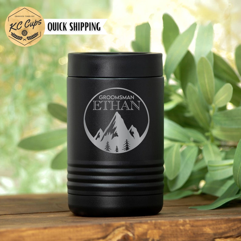 Pu&ograve; includere: Frigorifero per lattine in acciaio inox nero con un design di montagna e alberi. Il testo "GROOMSMAN ETHAN" &egrave; inciso sul frigorifero.